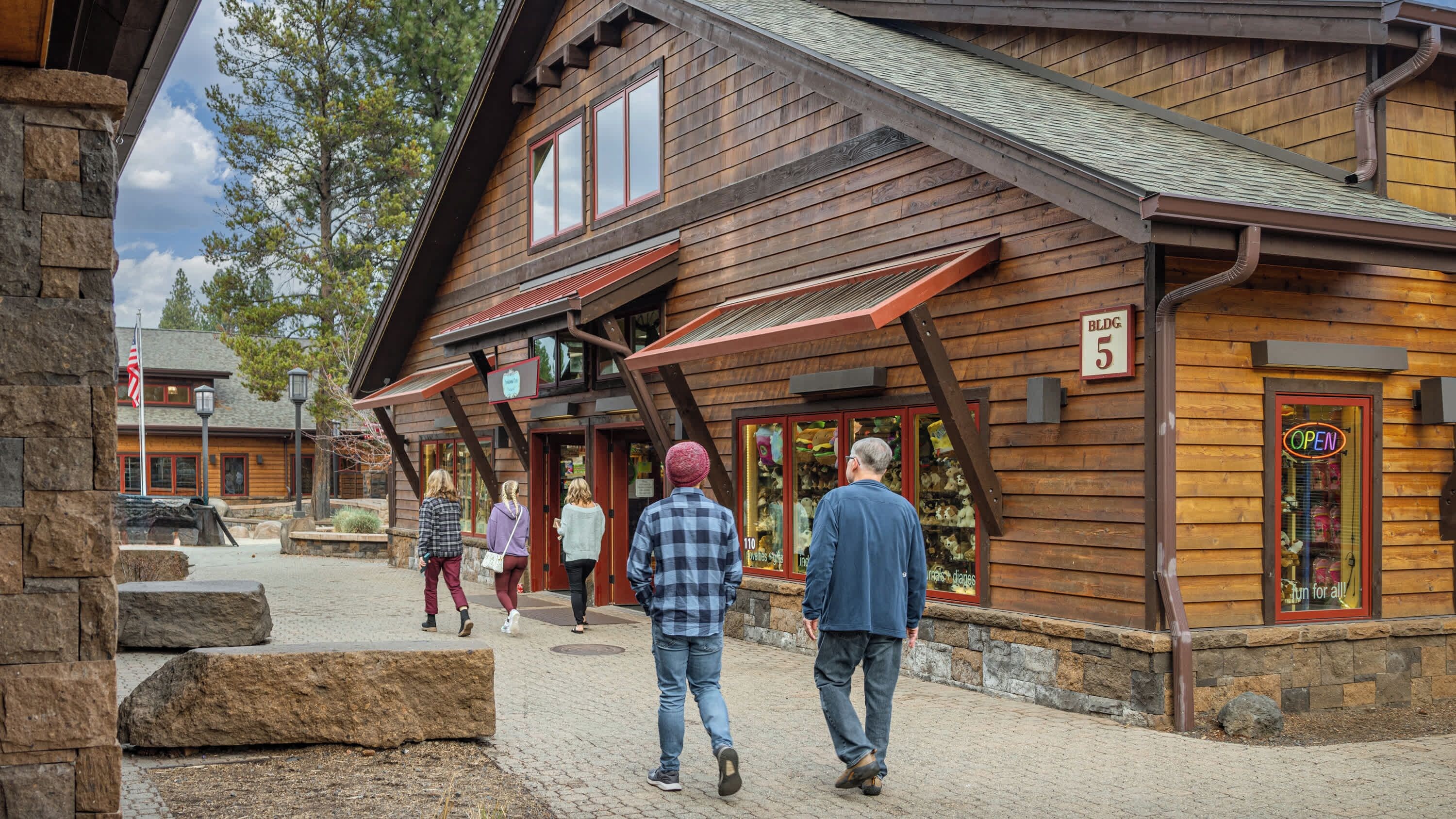 A wooden building with a stone facade, a sign indicating a business, and a paved area in front.