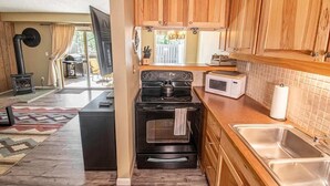 Une cuisine de taille réduite, dotée de meubles de rangement en bois, d’une cuisinière, d’un four à micro-ondes et d’un évier.