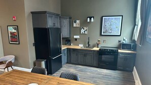Une cuisine moderne avec des meubles de couleur sombre, un réfrigérateur noir et une table à manger en bois.