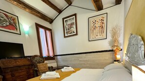 A hotel room with a wooden ceiling, a bed with white and yellow bedding, a dresser, a television, and artwork on the walls. - CA' DI LUNA VENEZIA  (Venice)