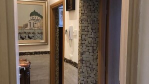 A hallway with a tiled wall, a framed picture of a building, and a telephone. - CA' DI LUNA VENEZIA  (Venice)