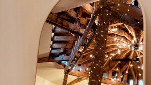 Une pièce dotée d’une structure de plafond en bois, d’un luminaire suspendu et d’un téléviseur posé sur un meuble.