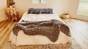 Une chambre à coucher avec un lit, une fenêtre, une table de chevet et un tapis.