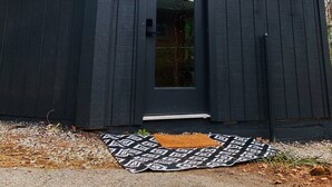 Une petite construction en bois sombre, dotée d’une seule porte et d’un petit espace porche.