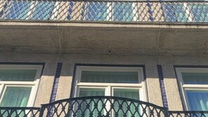 Ένα πολυώροφο κτίριο με μπαλκόνι που διαθέτει μεταλλική διακοσμητική πε ρίφραξη.