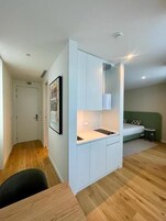 Habitación compacta con kitchenette, cama y una pequeña zona de estar.