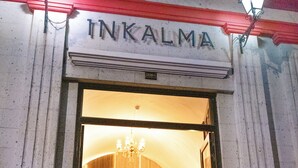 A building entrance with the name 'INKALMA' above the door, a chandelier inside, and two exterior wall-mounted lights. - HOTEL INKALMA SANTA MARTA (Arequipa)