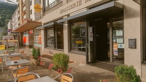 Un restaurant appelé « BRASSERIE DE LA POSTE », doté d’une terrasse et offrant une vue sur les montagnes.