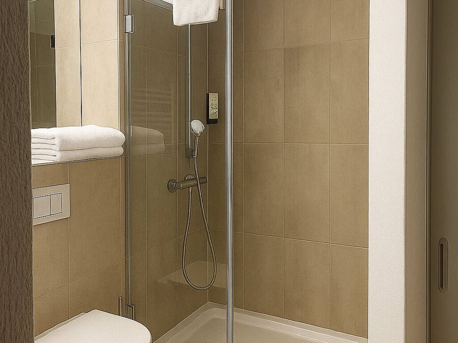 A modern bathroom with a glass-enclosed shower, a toilet, and a towel rack.