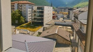 Une vue depuis une fenêtre donnant sur une ville, avec ses bâtiments, une montagne et un ciel dégagé.