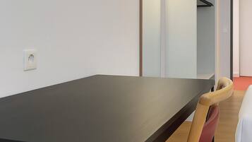 Una habitación moderna con una mesa de madera oscura, una silla tapizada en rojo y un aplique de pared.