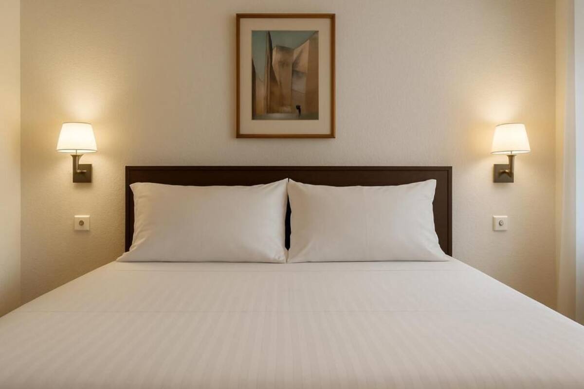 Une chambre d’hôtel avec un grand lit, deux lampes de chevet et un tableau encadré au mur.