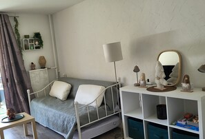 A bedroom with a bed, bedside table, lamp, mirror, and storage shelves.