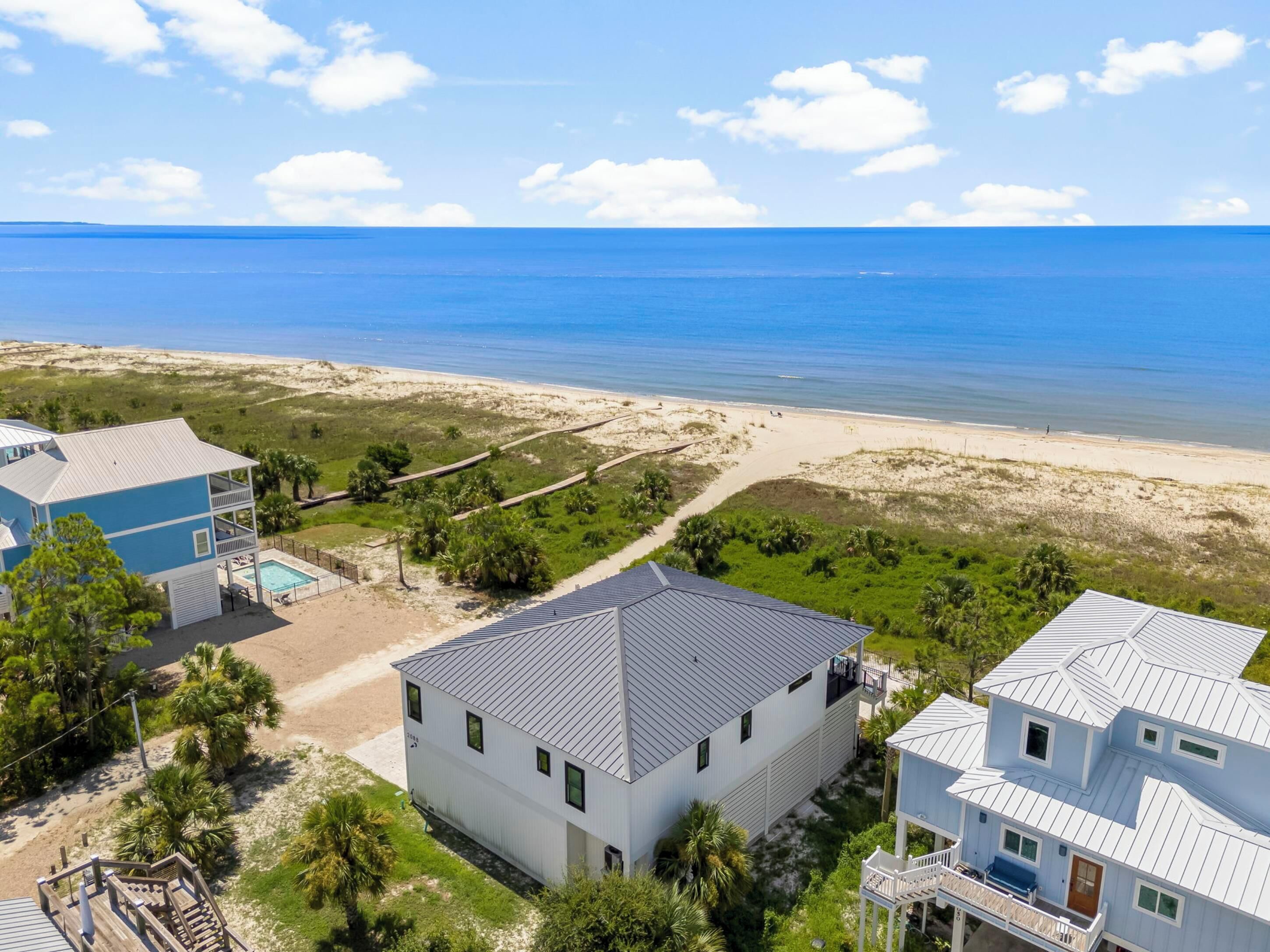 A coastal property with a large house, a pool, and a beach view.