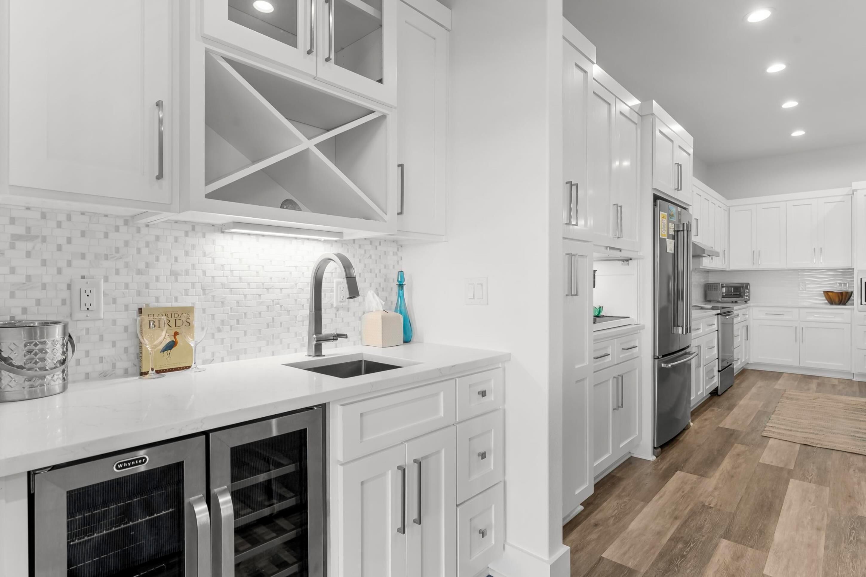 A modern kitchen with white cabinetry, stainless steel appliances, and a tiled backsplash.
