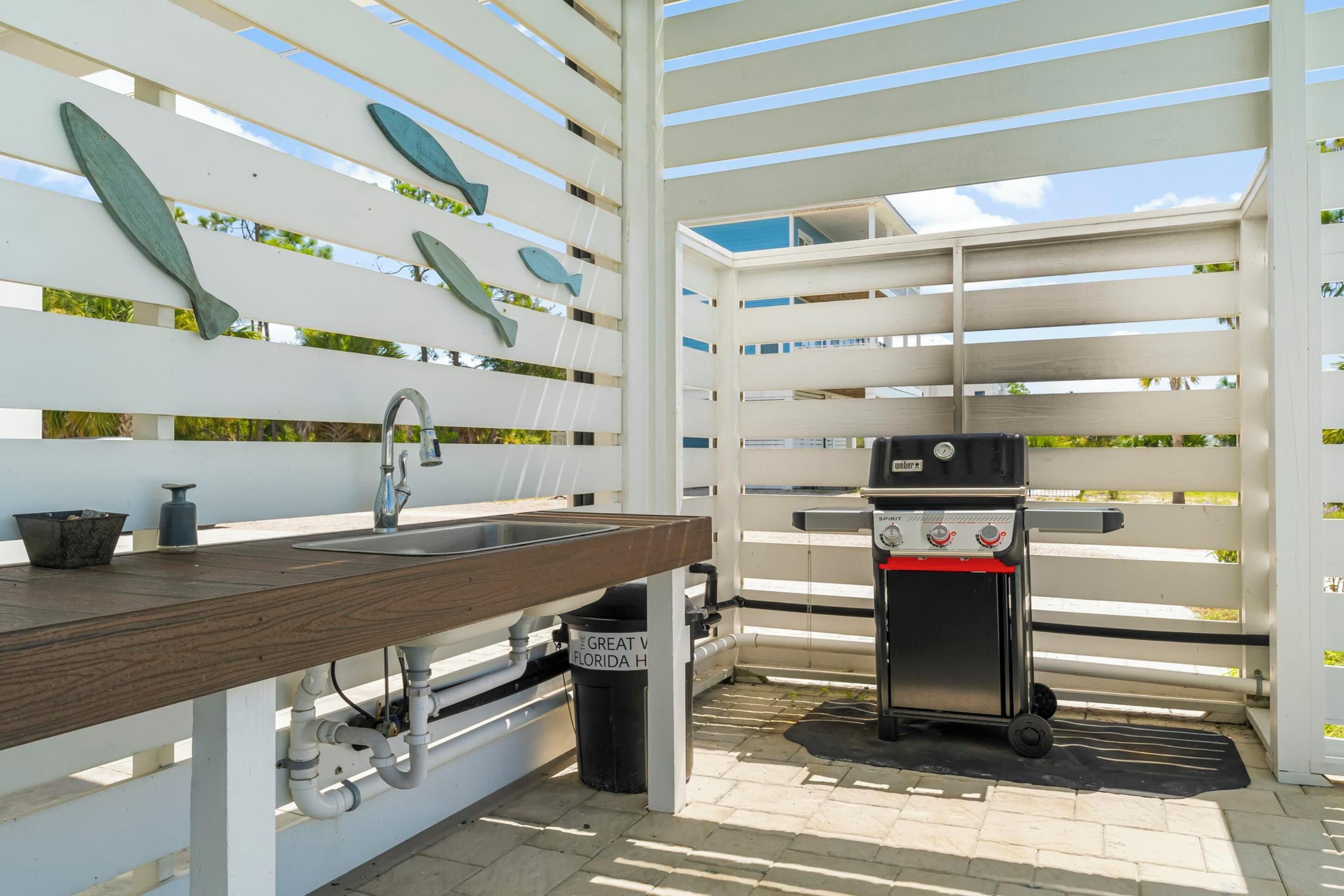 An outdoor kitchen area with a wooden countertop, a sink, and a portable grill.