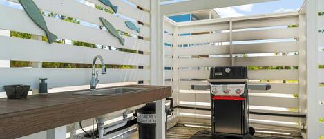 An outdoor kitchen area with a wooden countertop, a sink, and a portable grill.