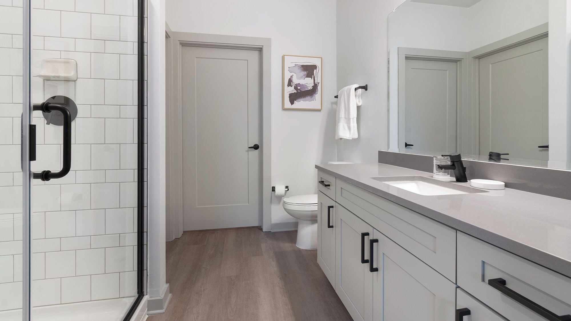 A modern bathroom with a shower, toilet, and vanity.