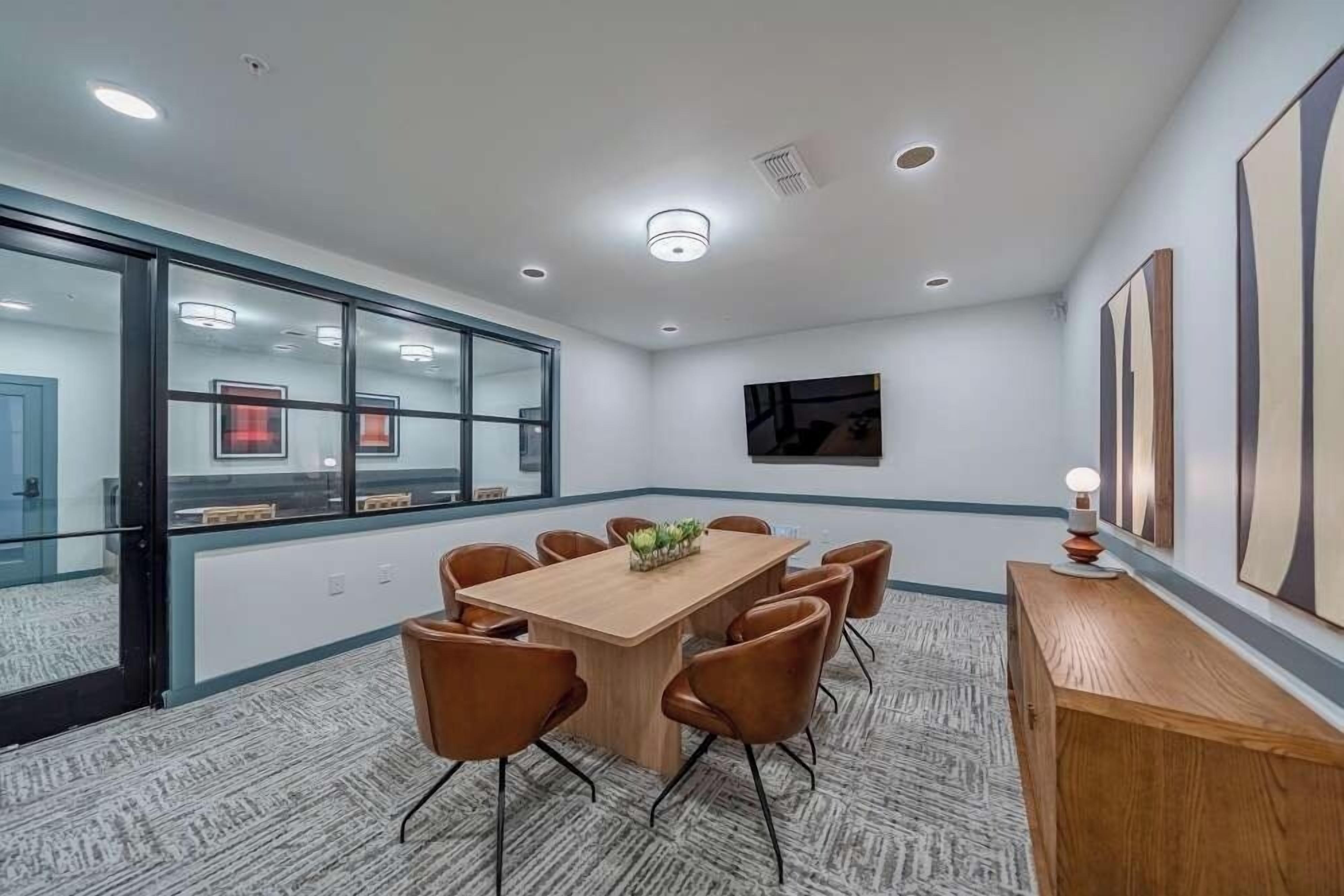 A conference room with a large table, chairs, and a carpeted floor.