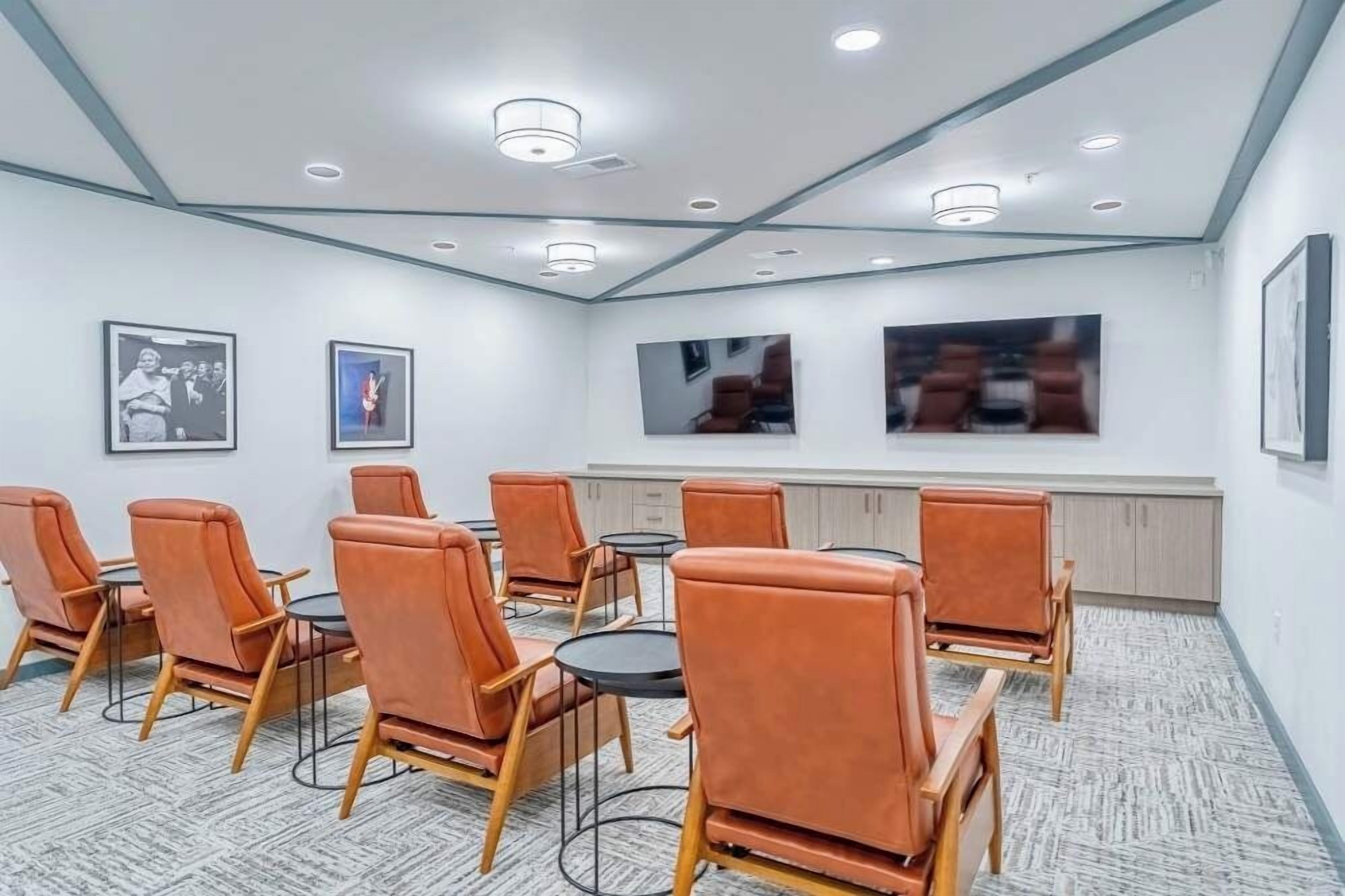 A conference room with a modern design, featuring leather chairs, round tables, and framed pictures on the walls.