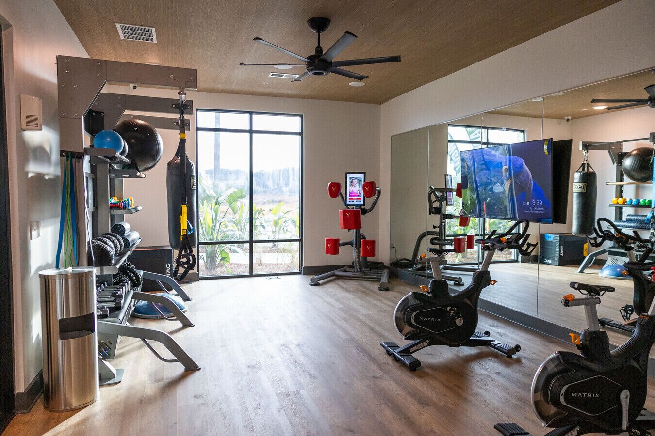 A gym with cardio machines, weightlifting equipment, and a large mirror.