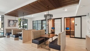 A modern lounge area with wooden panel ceiling, cushioned seating, and a central table. - Southbank Apartments by Landing (Jacksonville)