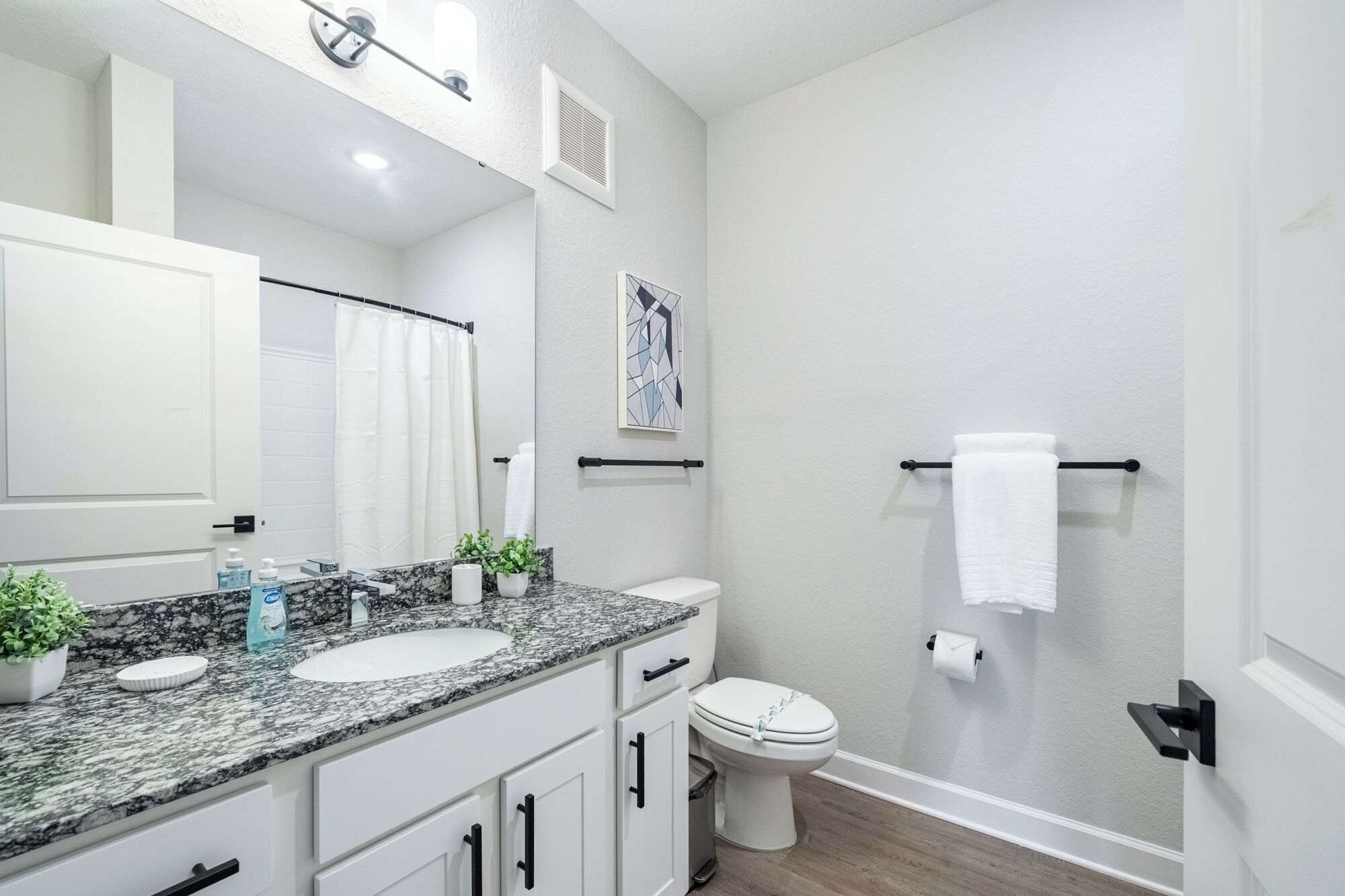 A modern bathroom with a white sink, a toilet, and a shower area.