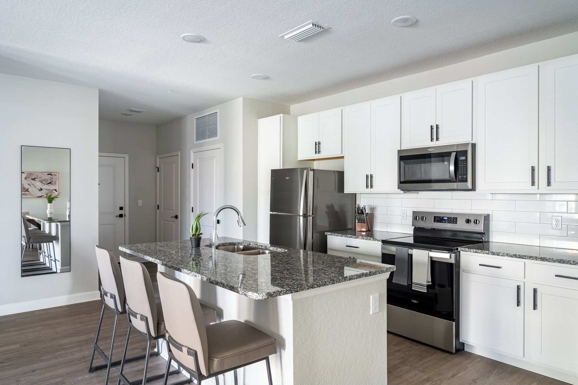 A modern kitchen with white cabinets, stainless steel appliances, and a granite countertop.