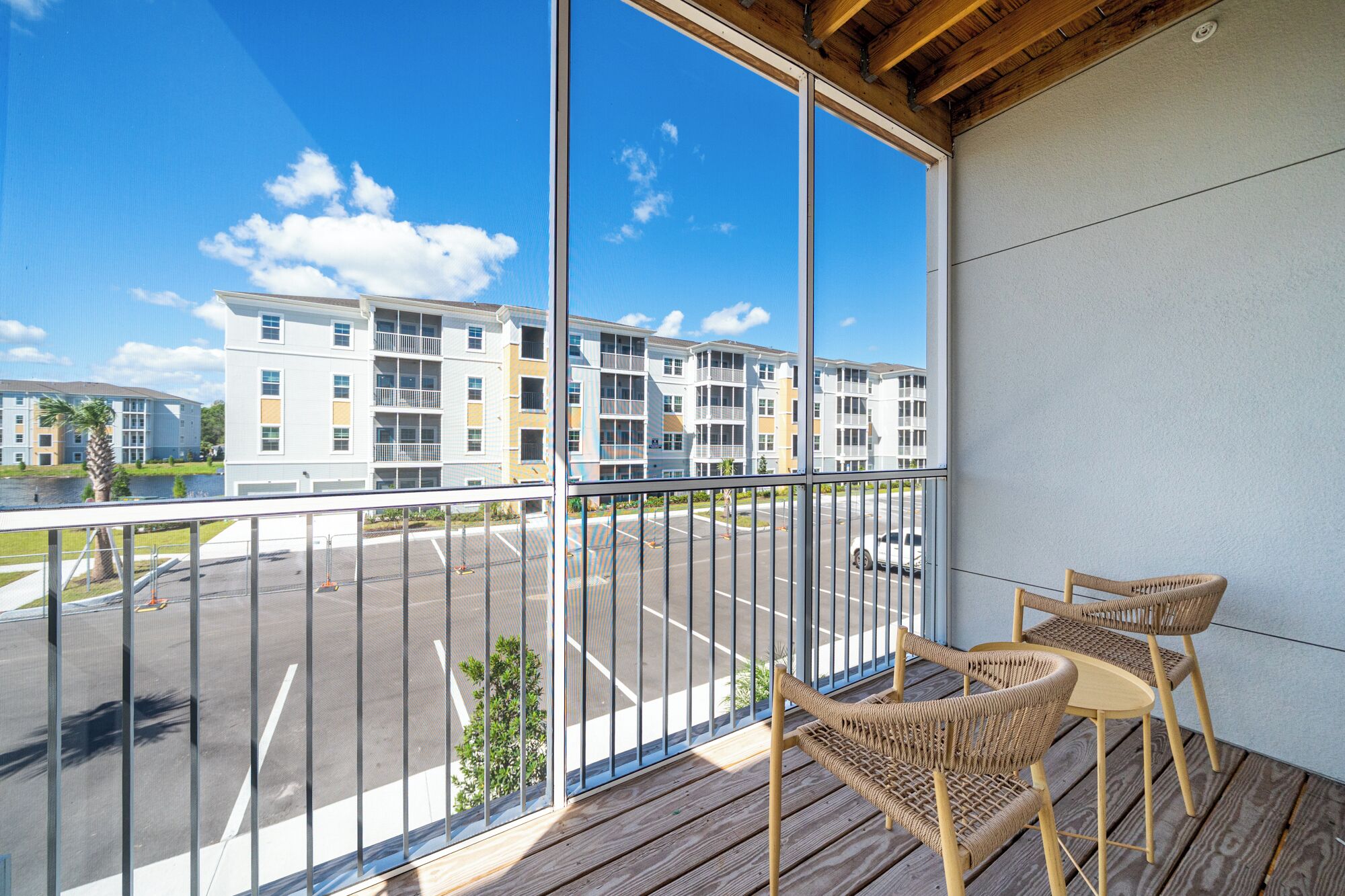 A balcony with wicker chairs and a view of a multi-story building with balconies.