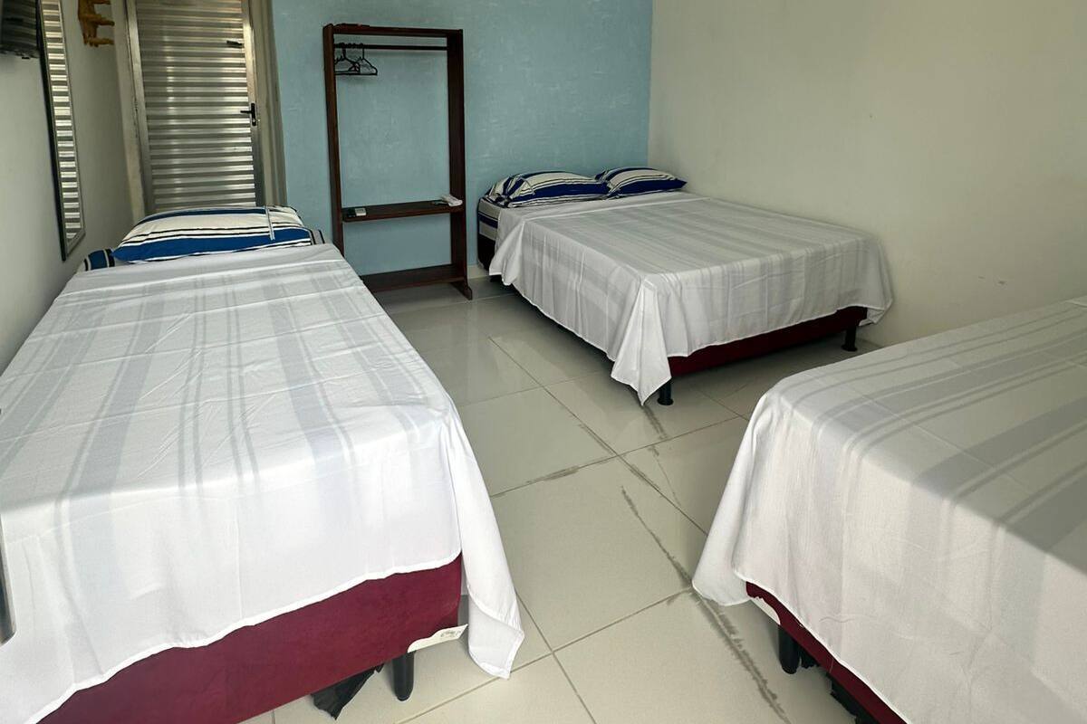 Een hotelkamer met drie enkele bedden, een kledingkast en een spiegel.