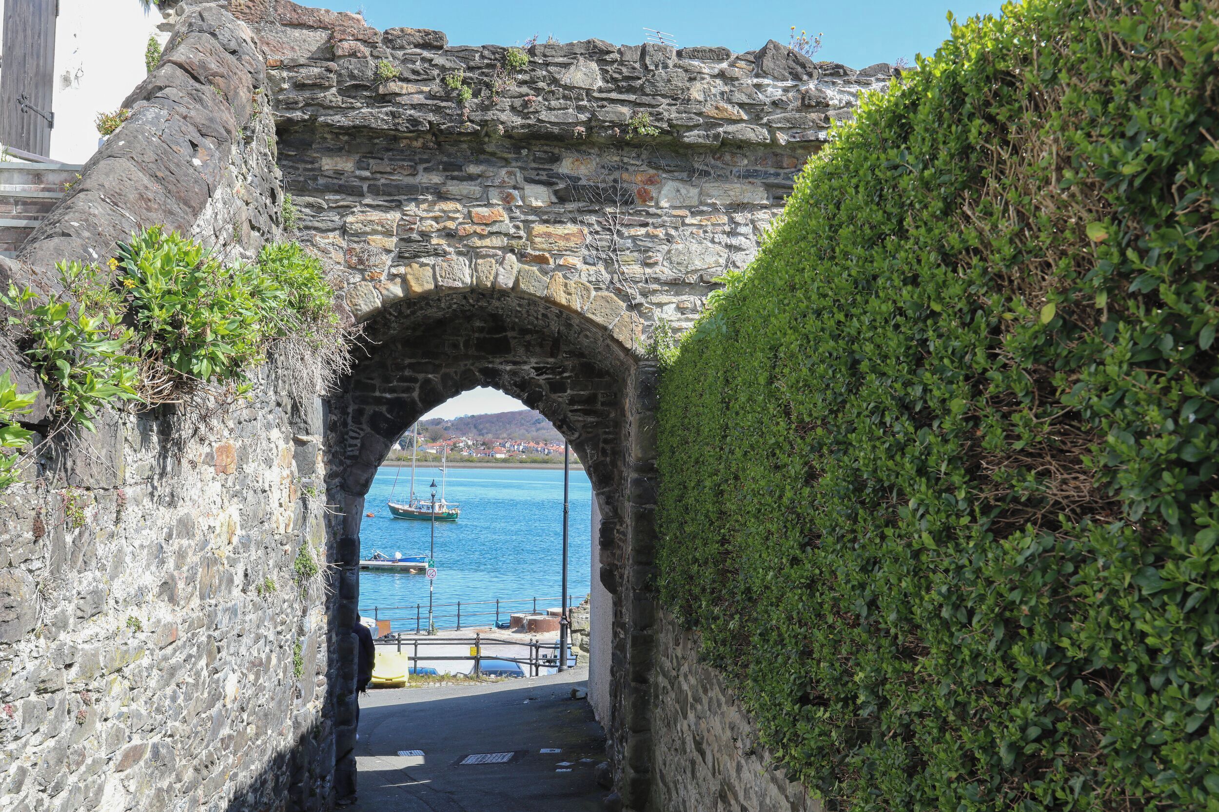 Un arco de piedra que da acceso a un puerto con barcos.