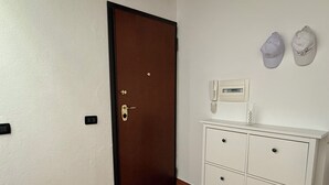 Ein Zimmer mit einer braunen Tür, einem weißen Kommode mit Schubladen und einem an der Wand montierten Telefon.