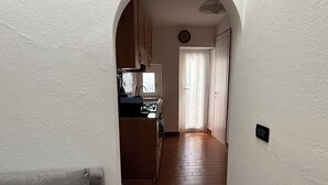Ein schmales Dielenkorridor führt zu einem Küchenbereich mit Holzausstattung und einem Fenster.