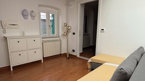 Ein Schlafzimmer mit einem Bett, einer Kommode, einem Heizkörper und einem Fenster mit Fensterläden.