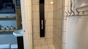 Un piccolo box doccia con pareti piastrellate e una porta nera.