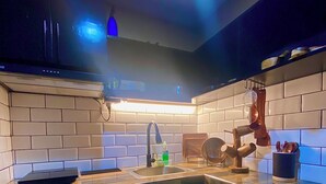 A modern kitchen with a black countertop, a sink, and a backsplash of white tiles. - IV’s Condo with AC, WiFi, Netflix in Cainta (Cainta)