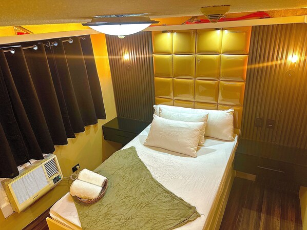 A compact hotel room with a bed, a bedside table, a lamp, and a window with curtains. - IV’s Condo with AC, WiFi, Netflix in Cainta (Cainta)