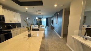 A modern kitchen with a central island, white cabinetry, and a large mirror. - 2 Bedrooms Apartment  in Storey Lake (Kissimmee)