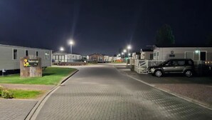 A row of mobile homes with a paved driveway and street lights. - Cozy Caravan , Free Wifi, Pet Friendly (Skegness)