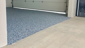A garage with a closed garage door, a blue textured floor, and a brown doormat.