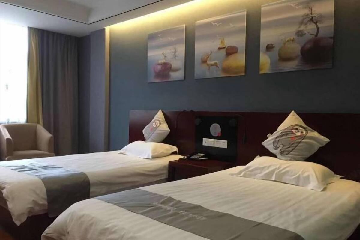 A hotel room with two beds, a chair, and artwork on the wall.