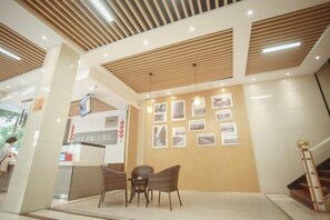 A reception area with a reception desk, chairs, and framed pictures on the wall.