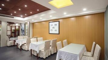 A conference room with tables and chairs, wooden panel walls, and a ceiling with recessed lighting.