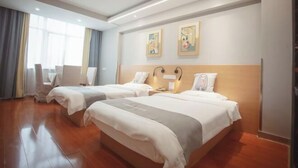 A hotel room with two beds, a desk, and a chair.