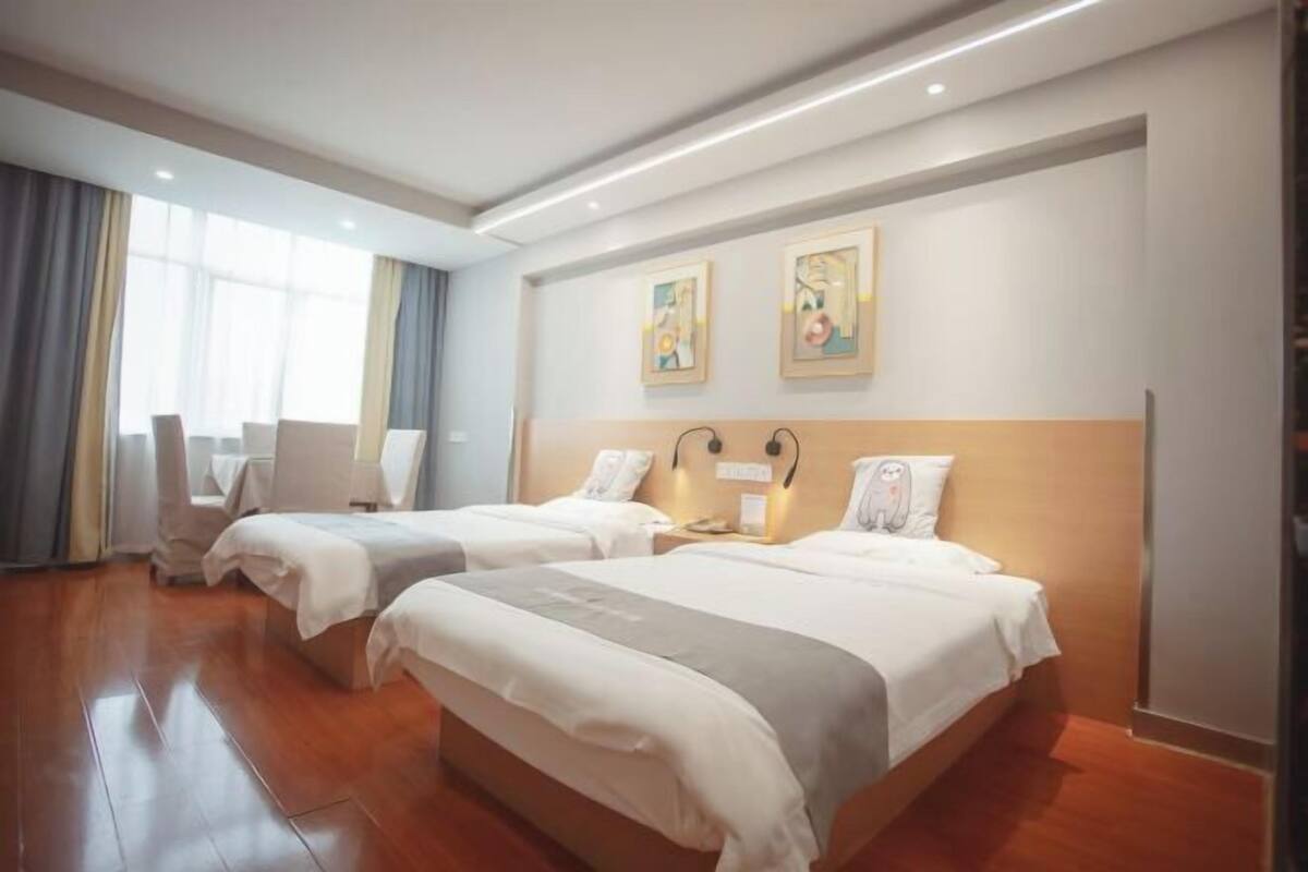 A hotel room with two beds, a desk, and a chair.