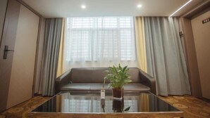 A modern room with a glass coffee table, a sofa, and a potted plant.