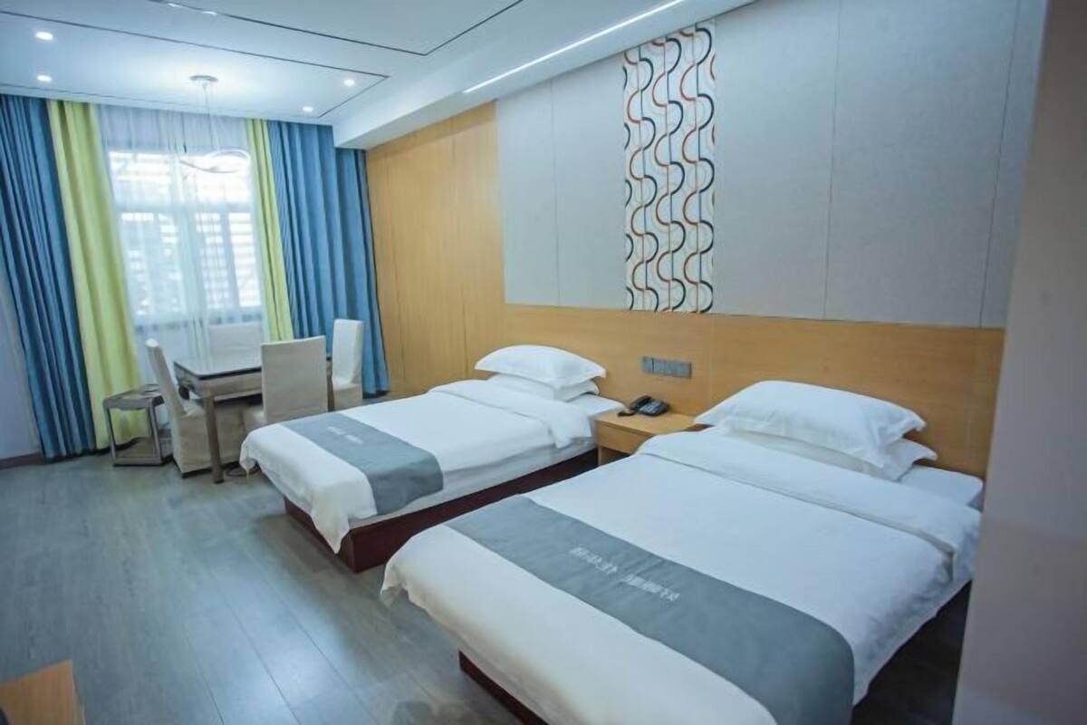 A hotel room with two beds, a desk, and a chair.