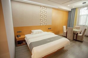 Une chambre d’hôtel moderne avec un grand lit, un bureau avec une chaise et un petit coin salon.