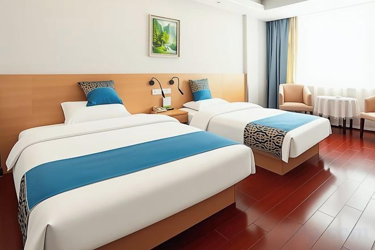 A hotel room with two beds, a desk, and a chair.