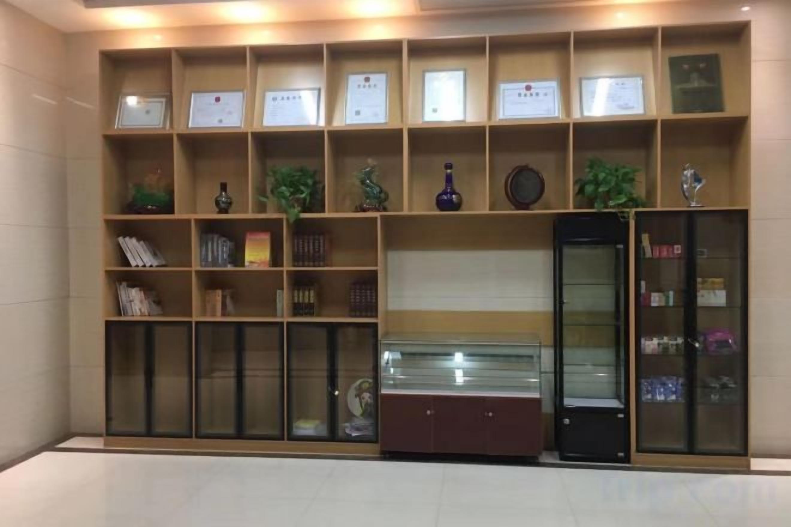 A reception area with a display of framed certificates, a glass display case, and a bookcase with books.